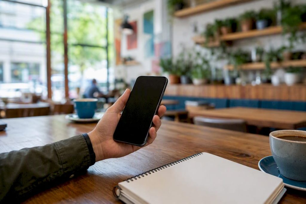 Hand holding smartphone over desk with sales receipts